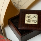 骨簽紅木盒裝紫檀七巧板<br/ ><b>Tangram puzzles and book</b><br /><em>Zitan</em> pieces in <em>hongmu</em> box with inscribed bone label<br />China; Qing dynasty, 19th c.<br />4.8 x 4.7 x 2.1 cm<br /><em>Yi Zhi Tang</em> Collection 71-023